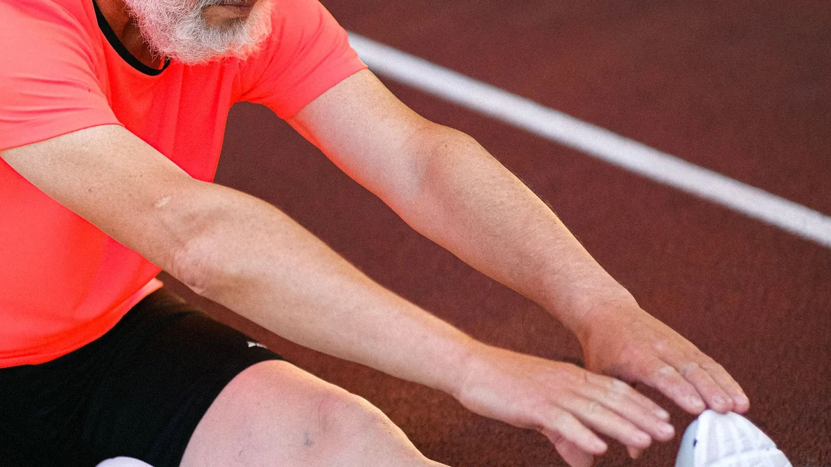 Older athlete stretching on a running track after training