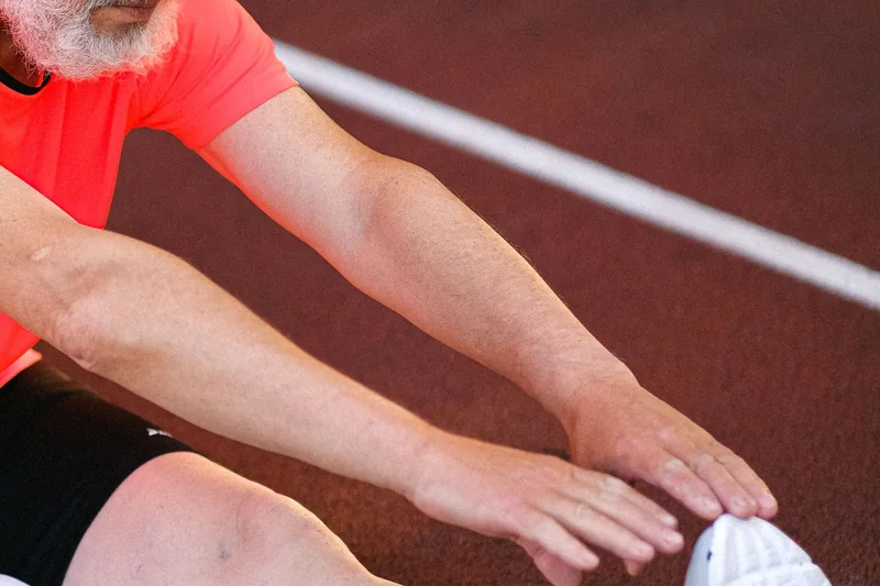 Older athlete stretching on a track before or after exercise